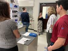 A group of people in a lab listening to a speaker