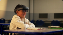 A child sitting in a desk using a ReadingXR HoloLens device