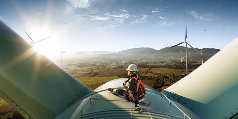 An apprentice sitting on top of a wind turbine